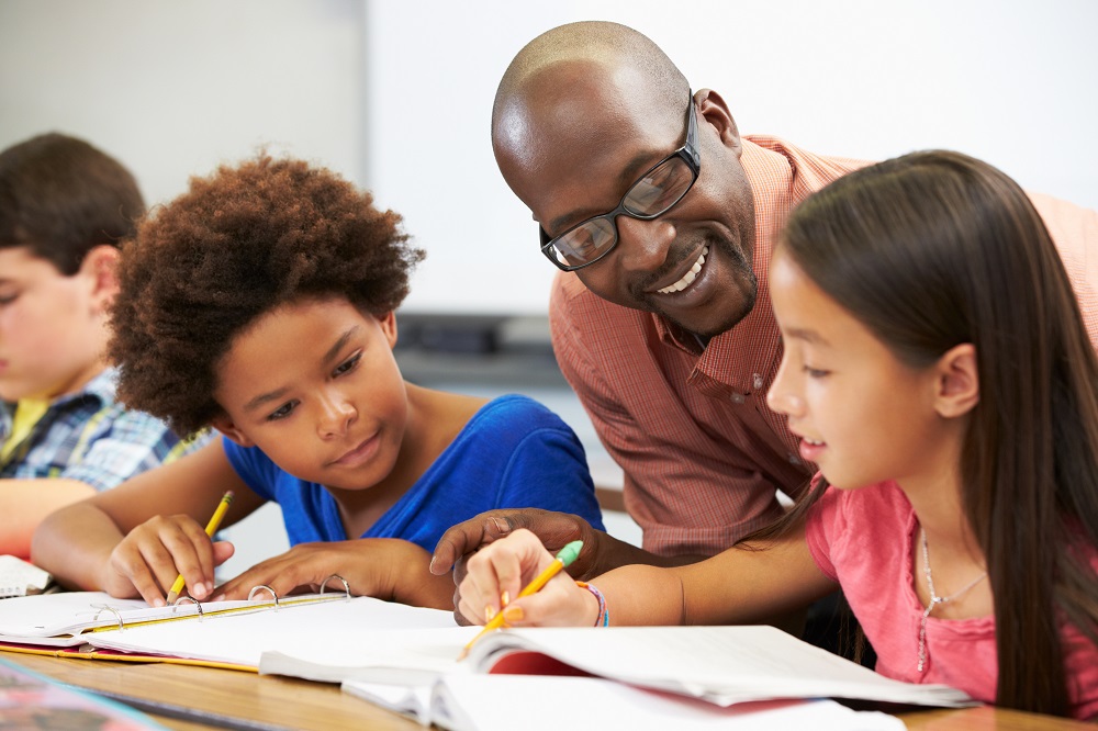 Male teacher helps out two students